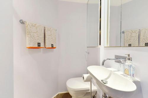 Baño blanco con aseo y lavamanos en Oxford Circus Station Apartment- Mayfair! en Londres