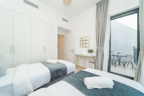 Habitación blanca con 2 camas y balcón. en Luxurious 3 BR with Maid Room in Arabian Ranches 2 en Dubái