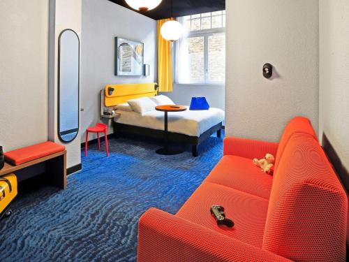 un soggiorno con divano rosso e letto di ibis Styles Saint Malo Centre Historique a Saint Malo