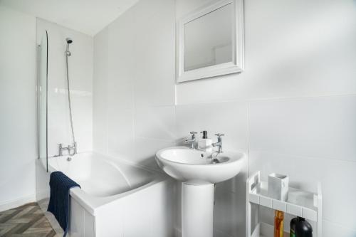 a white bathroom with a sink and a bath tub at 4Bed-Free Parking-Maisonette in Haltwhistle