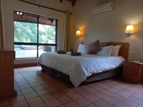 a bedroom with a large bed and a large window at Hoedspruit River Lodge in Hoedspruit