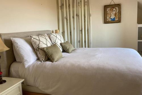 1 cama blanca con almohadas en el dormitorio en Drop Anchor House, Spacious 3 bedroom apartment, fabulous sea views, en Cleggan