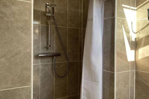 ducha con cabezal de ducha y cortina de ducha en Drop Anchor House, Spacious 3 bedroom apartment, fabulous sea views, en Cleggan