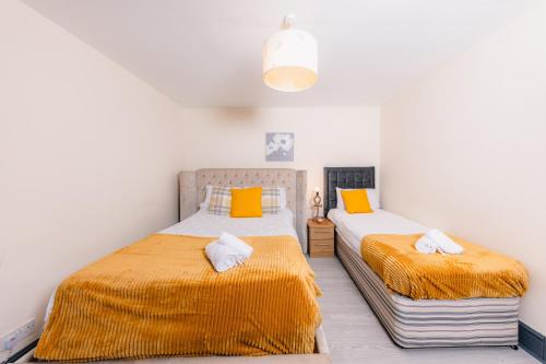 a bedroom with two beds with orange and white sheets at Warm&Welcoming City Centre Apartments by Meadows 3 in Edinburgh