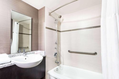 La salle de bains est pourvue d'un lavabo et d'une douche. dans l'établissement Ramada by Wyndham Ottawa On The Rideau, à Ottawa