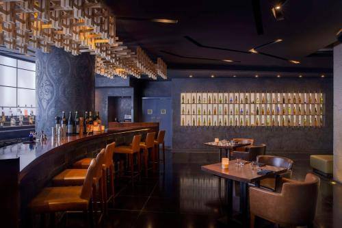 a bar with tables and chairs and wine bottles at Waldorf Astoria Ras Al Khaimah in Ras al Khaimah