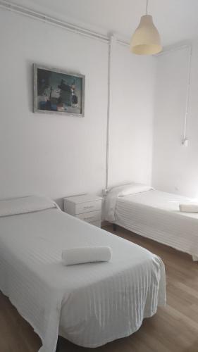een witte slaapkamer met 2 bedden en een foto aan de muur bij Arce apartamentos in Sevilla
