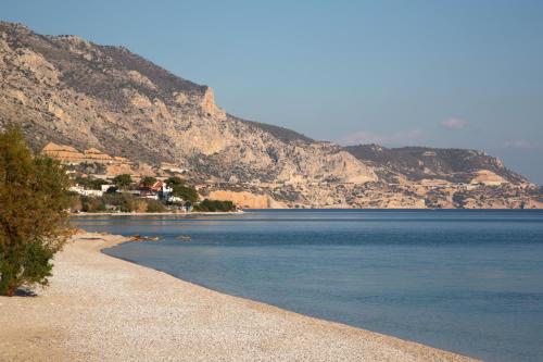 a beach next to a body of water with mountains at Kineta Seaside Summer Apartments in Kineta