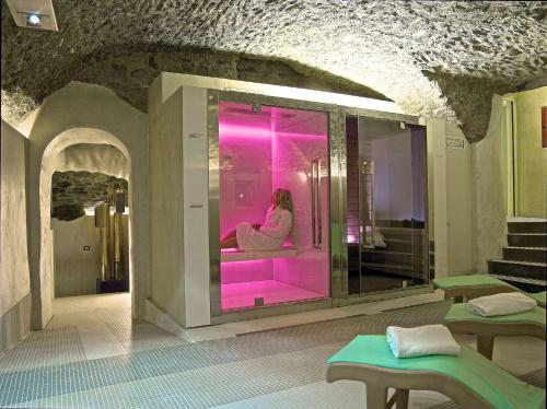 uma mulher sentada numa banheira num quarto com iluminação rosa em Hotel Centrale Best Western Signature Collection em Tirano