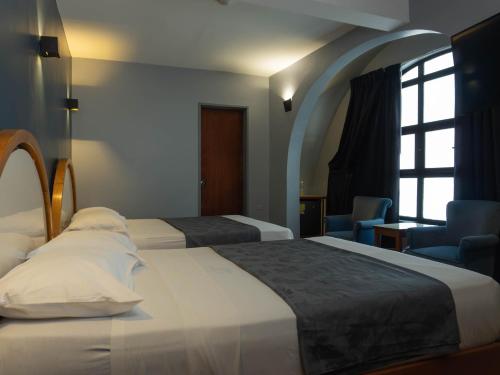 a hotel room with two beds and a window at Hotel El Arroyo in Caracas