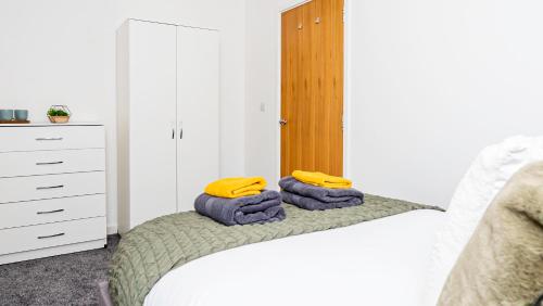 um quarto com uma cama com toalhas amarelas em Stunning flat near the Lake em Gosport