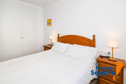 een slaapkamer met een bed met witte lakens en 2 lampen bij Casa Greco in Comarruga