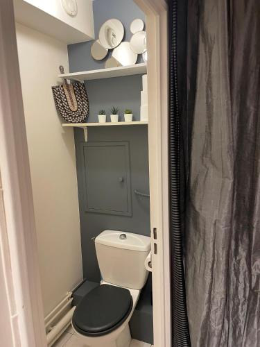 La salle de bains est pourvue de toilettes, d'un siège noir et d'étagères. dans l'établissement 2 pièces Asnières Idéal JO 2024, à Asnières-sur-Seine