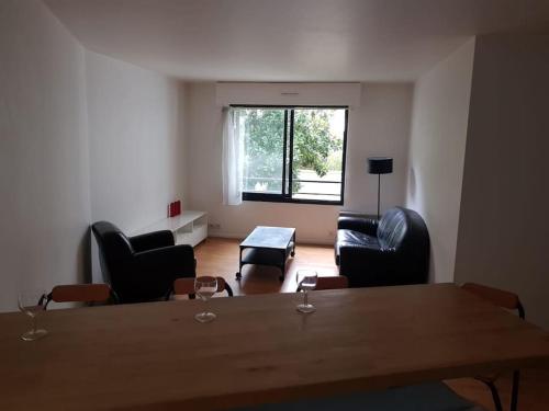 un salon avec une table et des chaises et une fenêtre dans l'établissement 2 pièces Asnières Idéal JO 2024, à Asnières-sur-Seine
