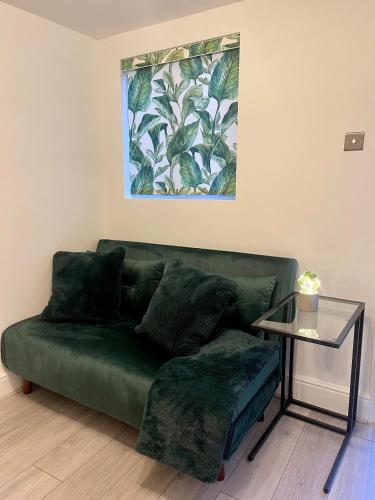 a green couch in a living room with a table at Zen Garden Hideaway. Close to Harry Potter&trains. in Watford