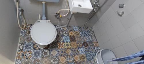 a bathroom with a toilet and a tile floor at SEAVIEW Room Bandra W Bandstand Nr Taj WOMEN ONLY in Mumbai