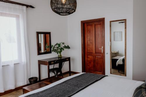 a bedroom with a bed and a desk and a mirror at Fritz Manor Bed and Breakfast in Swakopmund