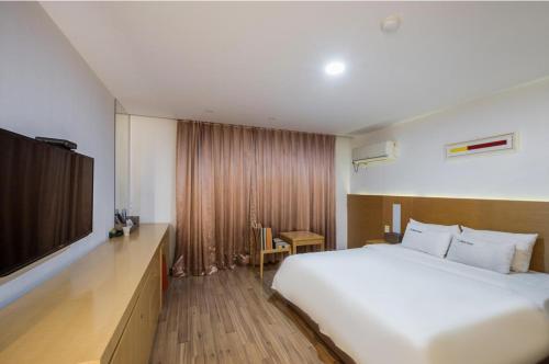 麗水的住宿－Wate Hotel，卧室配有一张白色大床和一台平面电视。