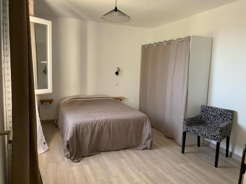 sypialnia z łóżkiem, krzesłem i lustrem w obiekcie Logement entier vue mer w Bastii