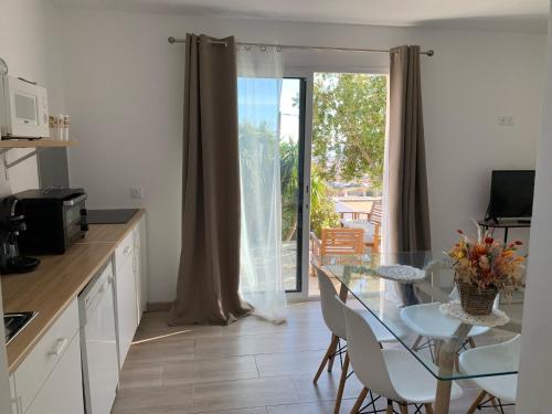uma cozinha com uma mesa de vidro e cadeiras e uma varanda em Logement entier vue mer em Bastia