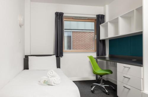 ルートンにあるWenlock Courtのベッド1台と緑の椅子が備わる小さな客室です。