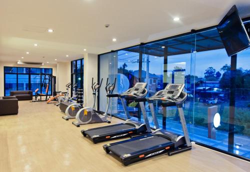 a gym with a row of cardio machines and windows at The Proud Hotel in Ubon Ratchathani