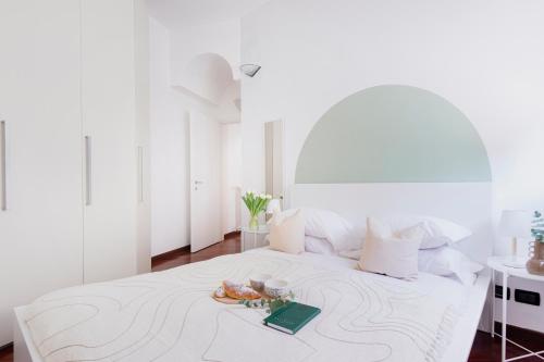 um quarto branco com uma cama com um livro em Stylish and Cozy apt close to Naviglio (MUDEC) em Milão