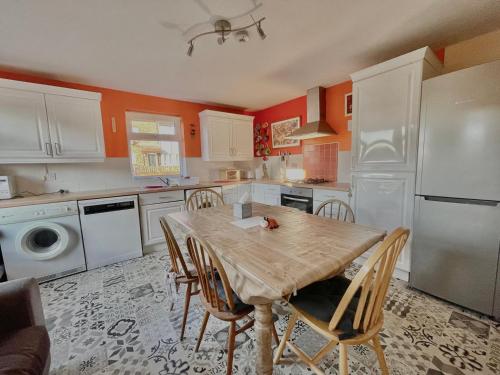 Il dispose d'une cuisine avec une table en bois, des chaises et un réfrigérateur. dans l'établissement GuestReady-Close To Leeds City, Spacious, Sleeps 6, à Leeds