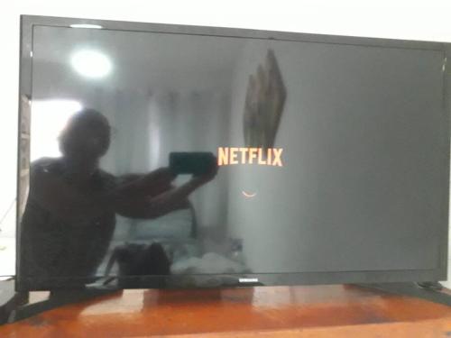 a person holding a camera in front of a television at Penedo - Quitinete para temporada in Itatiaia