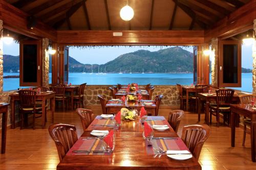 a restaurant with tables and chairs and a view of the water at Colibri Hotel in Baie Sainte Anne