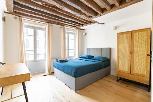 - une chambre avec un lit bleu dans une pièce dotée de fenêtres dans l'établissement Appartement Quartier Fontaine Chatelet Les Halles Free Netflix, à Paris