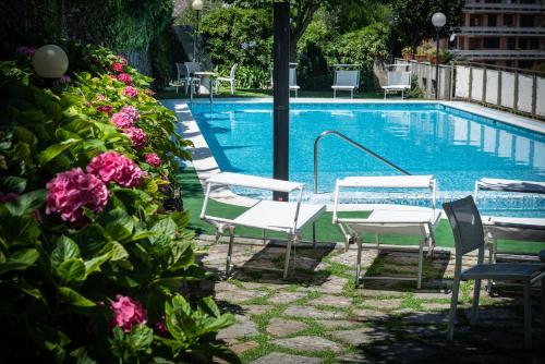 a pool with chairs and a table and flowers at Manuelina Taste Hotel in Recco