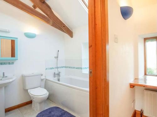 a bathroom with a toilet and a tub and a sink at Stunning Coastal Barn Conversion in Kingsbridge
