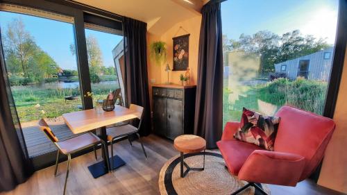 a living room with a desk and a chair and a table at Tiny House De Skries in Westergeest