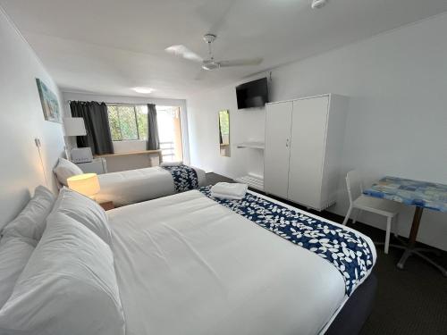 a bedroom with a large white bed and a desk at Browns Broadbeach in Gold Coast