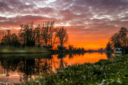 a sunset over a lake with a boat in the water at Tiny House De Skries in Westergeest