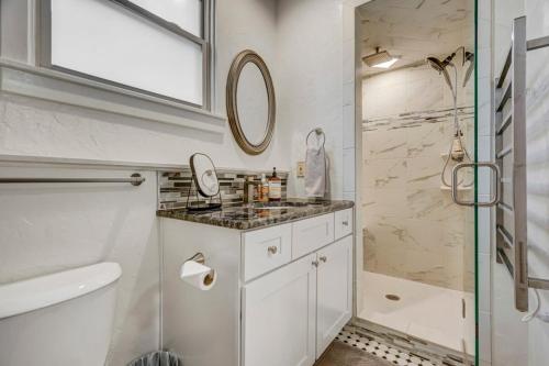 a white bathroom with a sink and a shower at Miners Anvil - Steps to Historic District in Colorado Springs