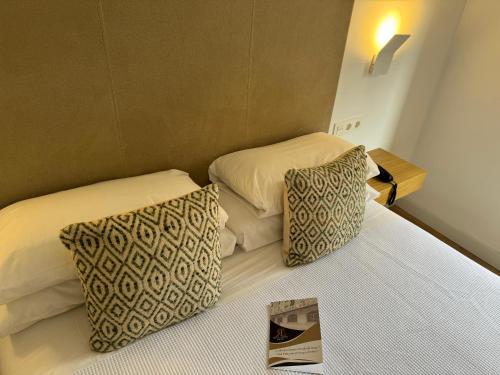 a hotel room with two beds and a magazine on the bed at Hotel RL Anibal in Linares