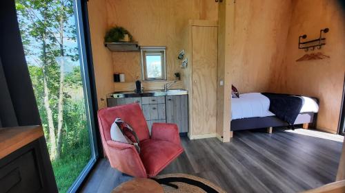 a room with a bedroom with a bed and a chair at Tiny House De Skries in Westergeest