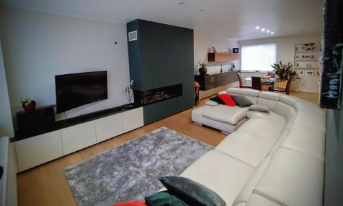 ein Wohnzimmer mit einem weißen Sofa und einem Flachbild-TV in der Unterkunft Zonnezoen in De Panne