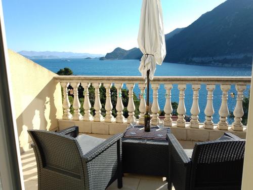 a table with an umbrella on a balcony overlooking the water at Apartments Laura Mljet in Sobra