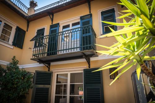 a building with green shutters and a balcony at Manuelina Taste Hotel in Recco