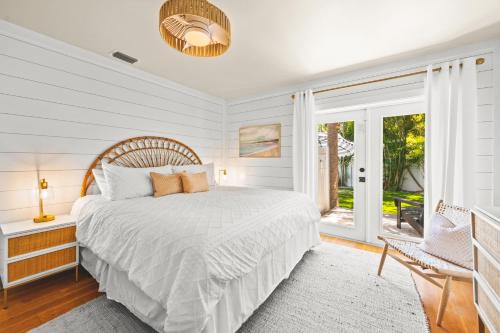 a white bedroom with a bed and a window at The Cottage on Pine - Luxury Boho Beach Cottage wPvt Heated Pool On Pine Ave in Anna Maria