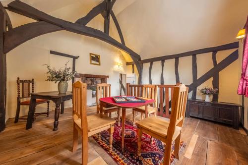 a dining room with a wooden table and chairs at Medieval cottage in rural village - Duke's Lodge in Bildeston