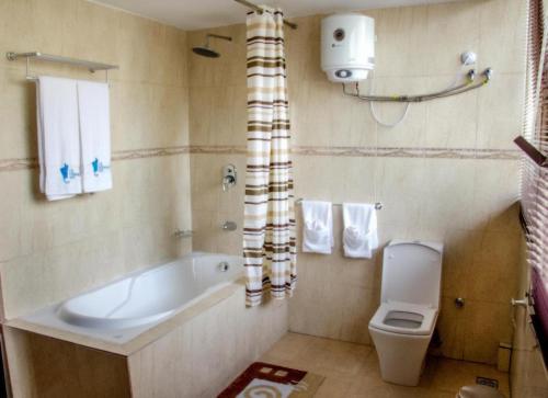 a bathroom with a bath tub and a toilet at The Chesterfield Hotel in Lagos