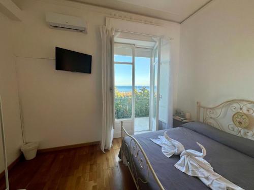 een slaapkamer met een bed en een glazen schuifdeur bij Villa Jole Faraglioni Acitrezza in Aci Castello