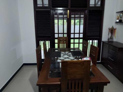 ein Esszimmer mit einem Holztisch und Stühlen in der Unterkunft Hesali villa in Telwatta