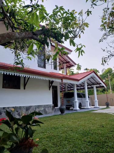 ein weißes Haus mit rotem Dach und einem Auto geparkt in der Unterkunft Hesali villa in Telwatta