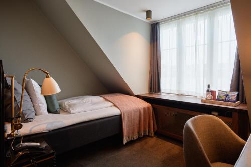 a bedroom with a bed and a window with a lamp at Hotel Skt. Annæ in Copenhagen