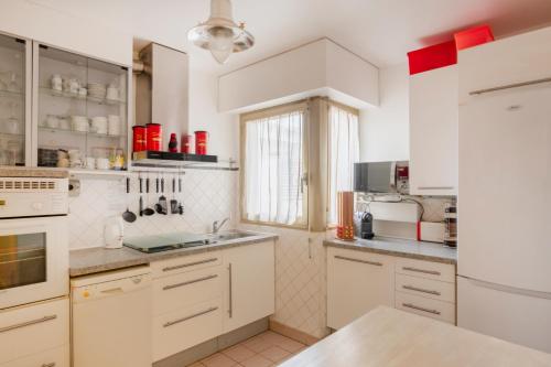 eine weiße Küche mit weißen Schränken und Geräten in der Unterkunft Paris Beaugrenelle Residence in Paris